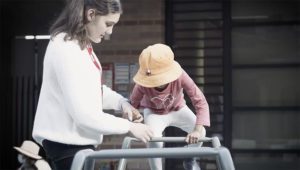 Amelia Crecca, Diploma Trainee Educator, assists a small child on play equipment