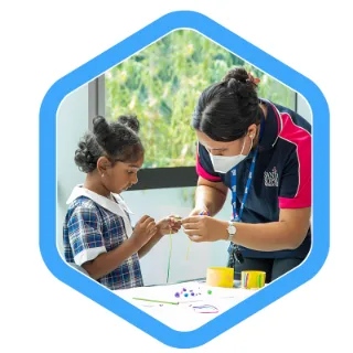 an ambrose school age care educator assists a school age child with craft activities