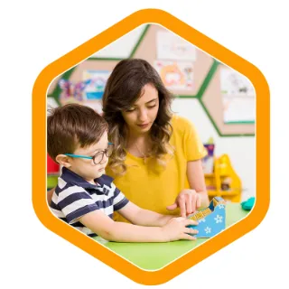 an ambrose early learning educator teaches a small boy who is wearing eye glasses